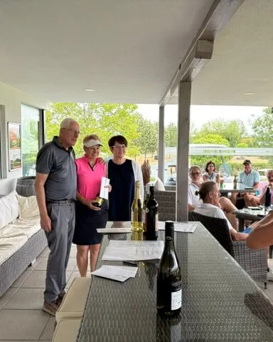 Drei Personen bei Siegerehrung mit Preisen und Flaschen auf einem Tisch in Österreich